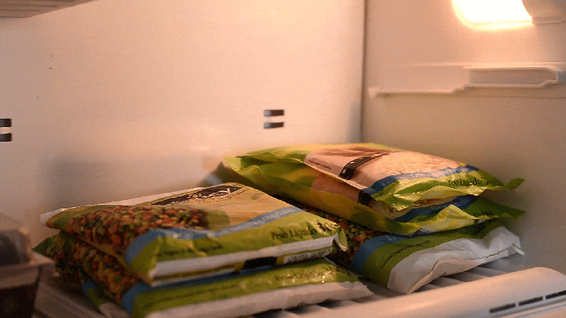 Mão feminina retirando pacote de legumes congelados Daucy do freezer